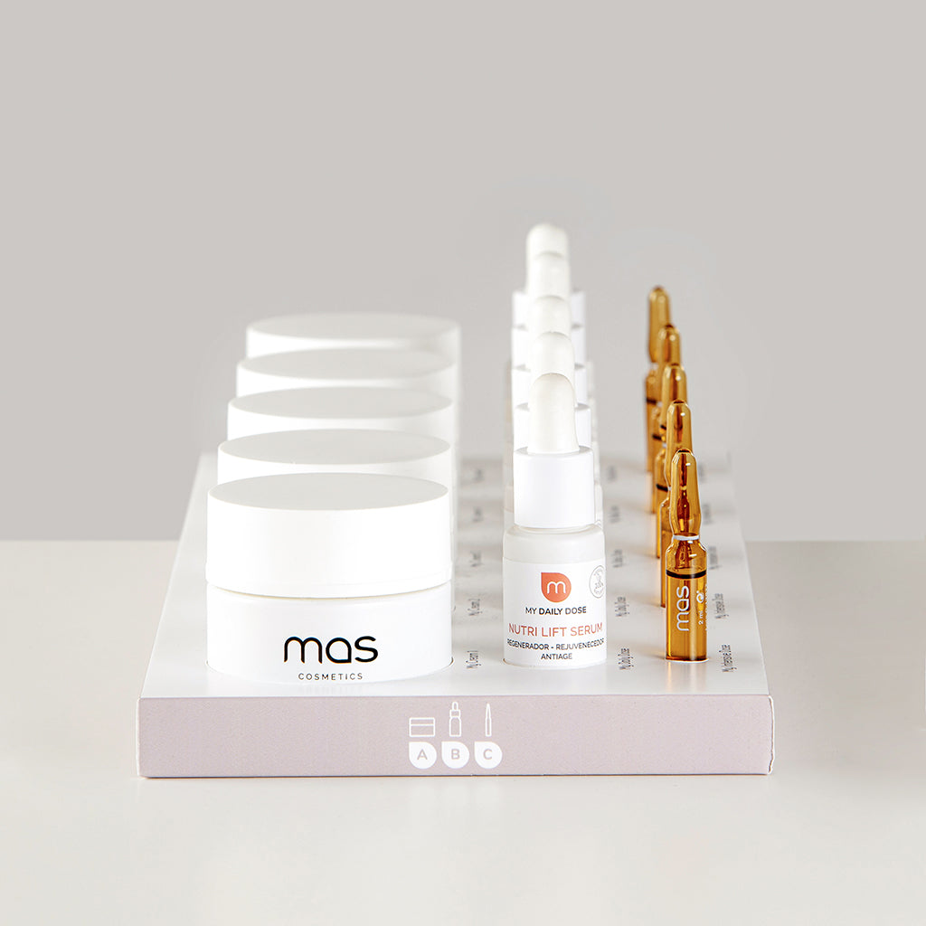 Selección de cosméticos MAS Cosmetics con cremas faciales, sérums y ampollas, presentados en un expositor de la marca.
